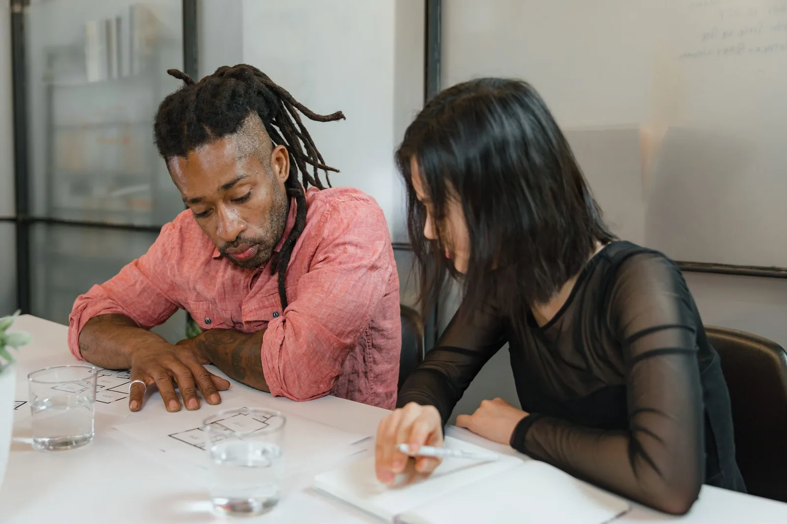 Two nonprofit staff members reviewing campaign numbers on a laptop and notepad in an office