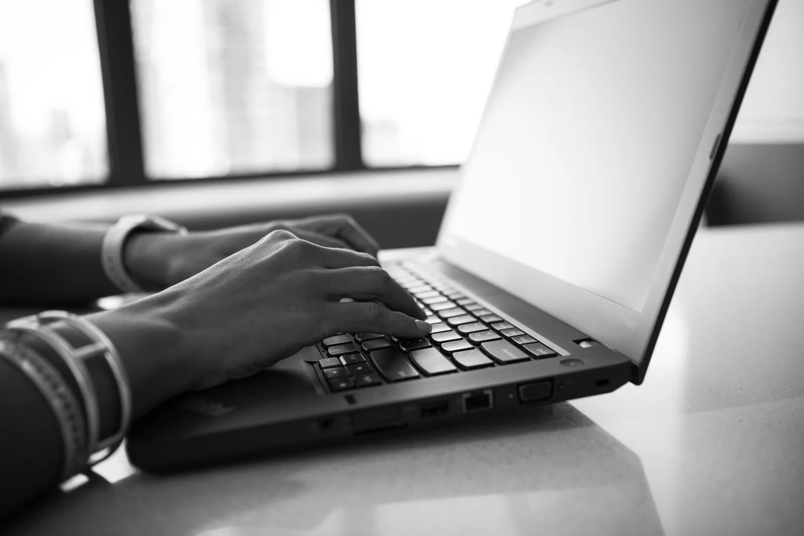 A nonprofit treasurer reviewing donation setup on a laptop at a table with paperwork and a notebook.