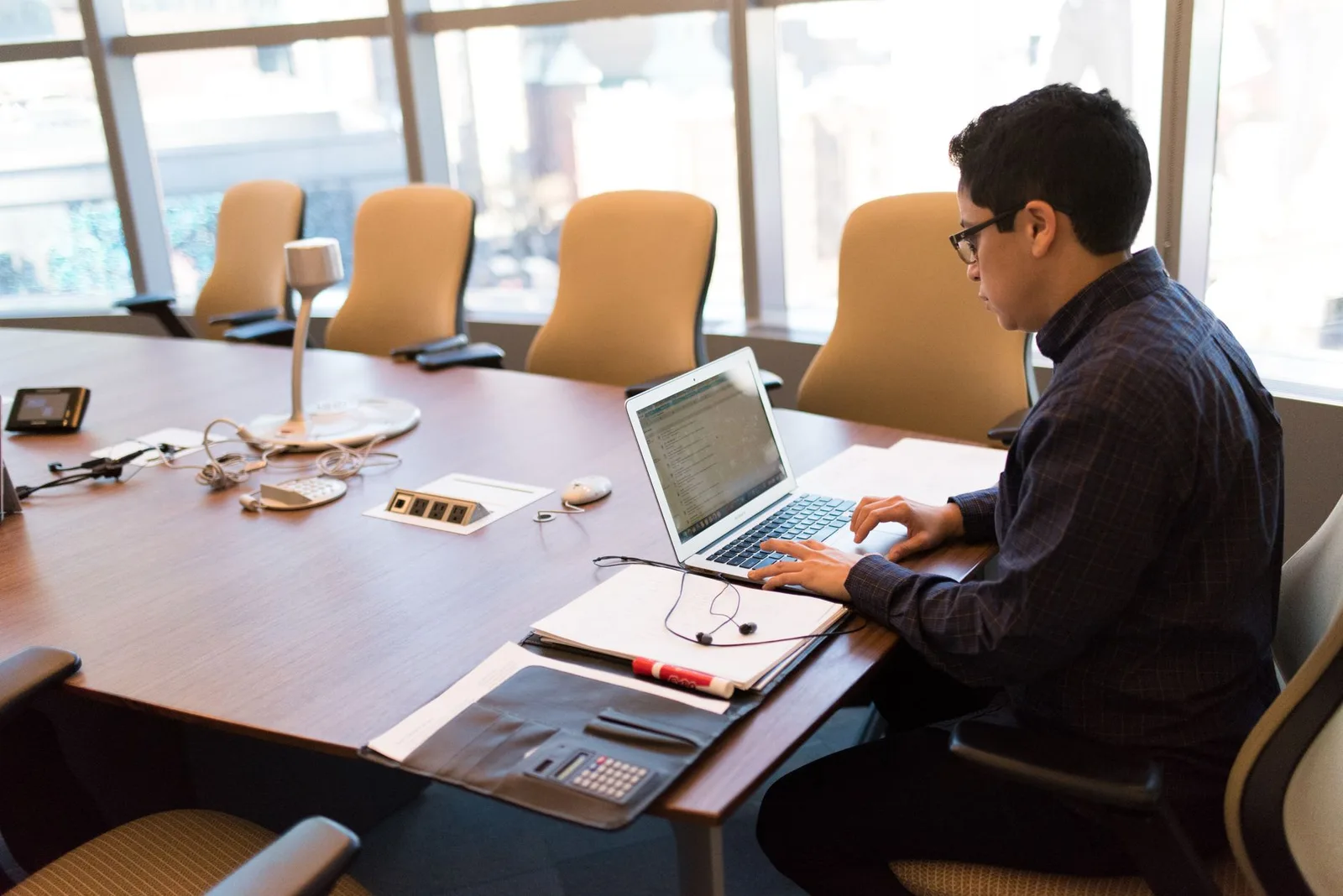 A nonprofit treasurer reviewing donation payments on a laptop at a table with notes and a phone nearby
