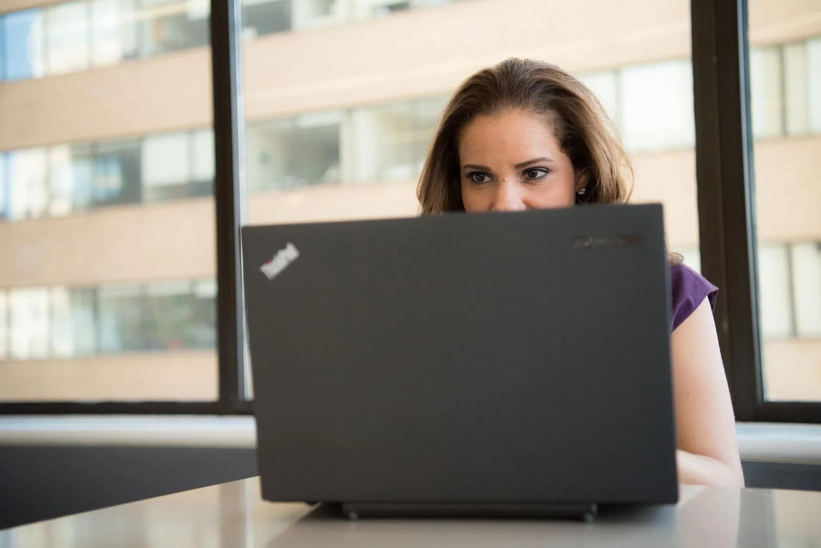 A nonprofit treasurer reviewing fundraising costs on a laptop at a table with notes and a calculator.
